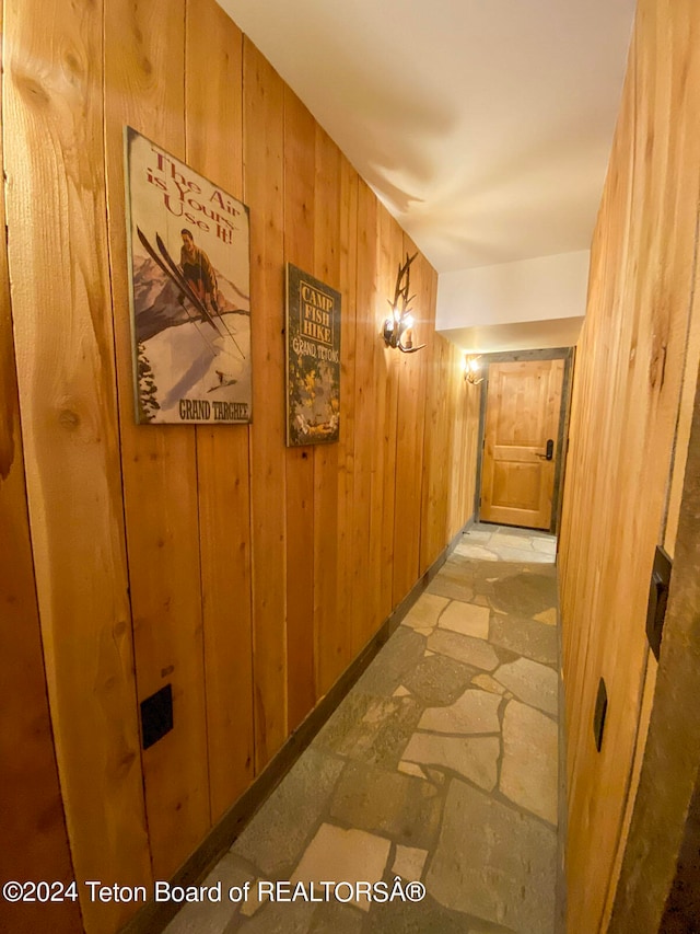 hallway featuring wood walls and light tile floors