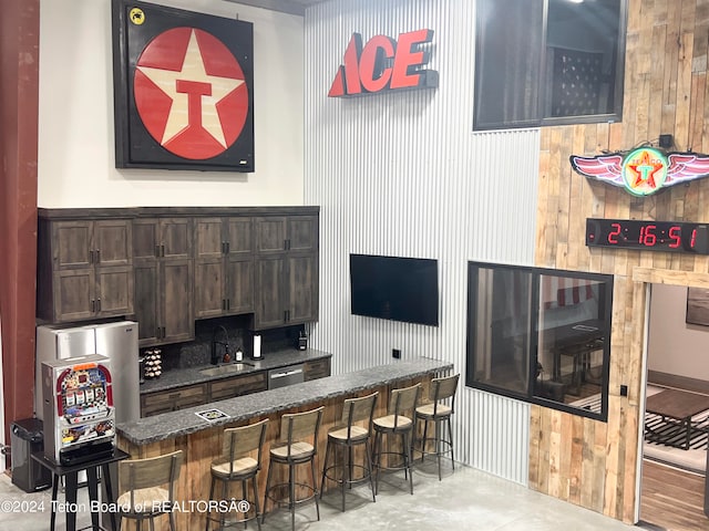 interior space featuring appliances with stainless steel finishes, dark brown cabinets, wooden walls, and sink