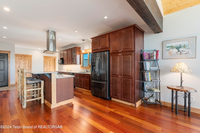 kitchen with hanging light fixtures, a breakfast bar, island exhaust hood, stainless steel refrigerator with ice dispenser, and dark hardwood / wood-style floors