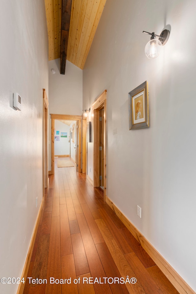 hall with lofted ceiling with beams, wood ceiling, and hardwood / wood-style floors