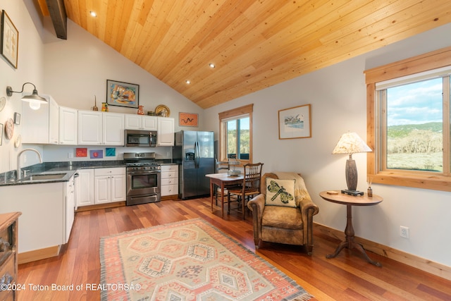 kitchen with appliances with stainless steel finishes, light hardwood / wood-style floors, white cabinetry, wooden ceiling, and sink