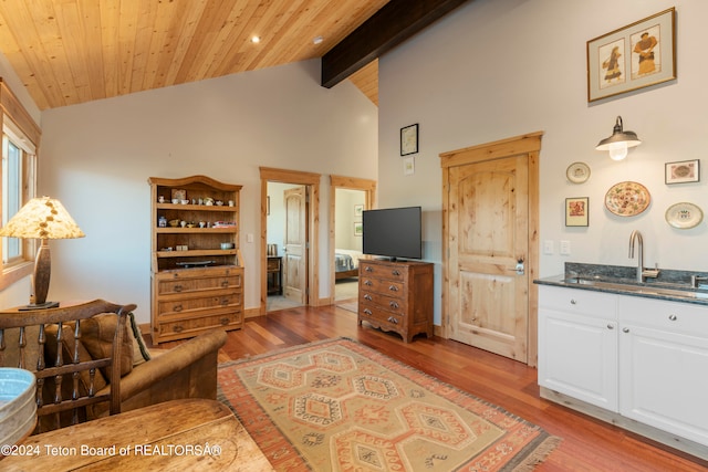 living room featuring light hardwood / wood-style flooring, beamed ceiling, wooden ceiling, and sink