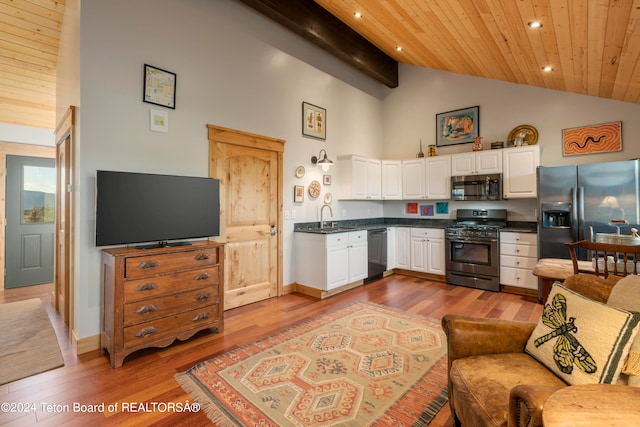 kitchen with white cabinets, stainless steel appliances, light wood-type flooring, and high vaulted ceiling