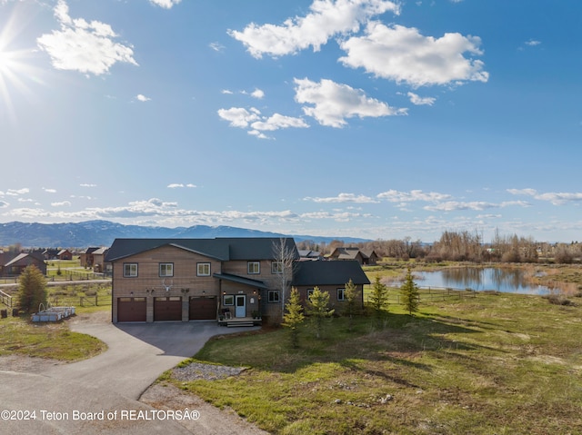 view of front of house featuring a water and mountain view, a garage, and a front yard