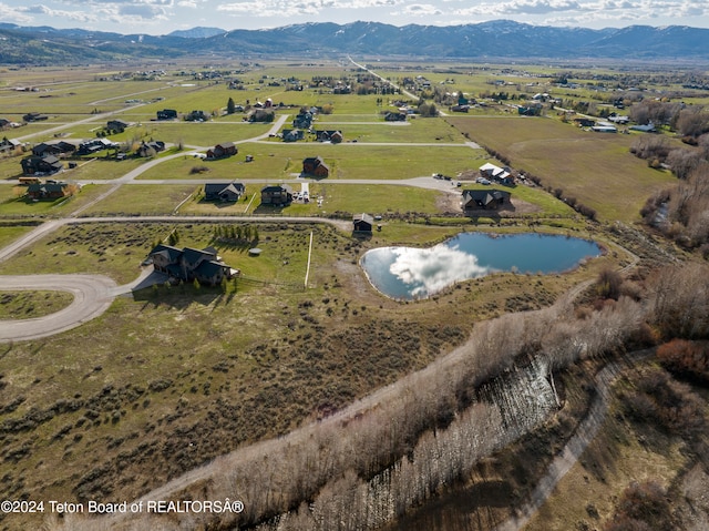 birds eye view of property featuring a water and mountain view and a rural view