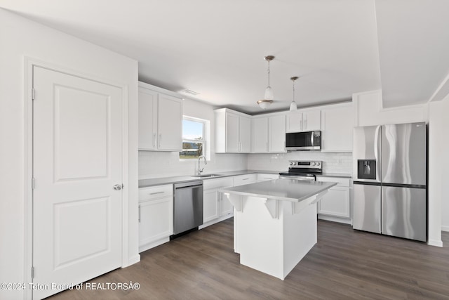 kitchen with hanging light fixtures, white cabinetry, appliances with stainless steel finishes, dark hardwood / wood-style floors, and a center island