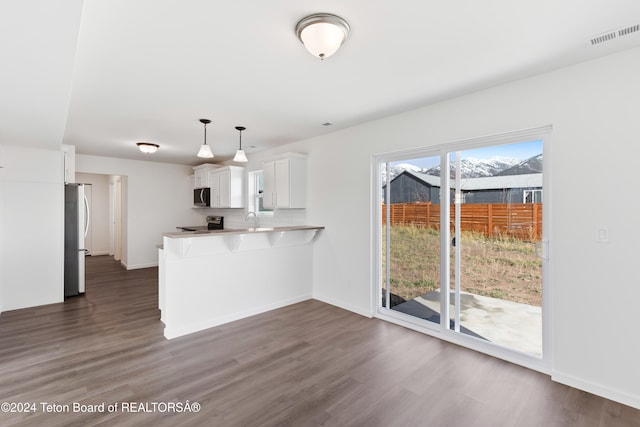 kitchen featuring plenty of natural light, kitchen peninsula, appliances with stainless steel finishes, and white cabinets