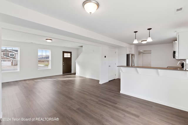 kitchen featuring stainless steel refrigerator, dark hardwood / wood-style flooring, hanging light fixtures, sink, and white cabinets