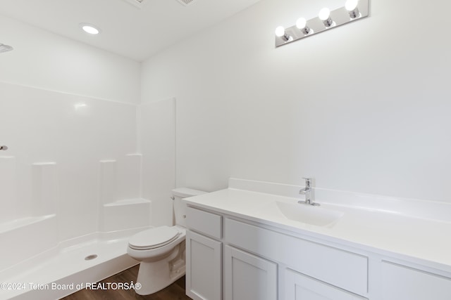 bathroom featuring toilet, vanity, hardwood / wood-style floors, and walk in shower