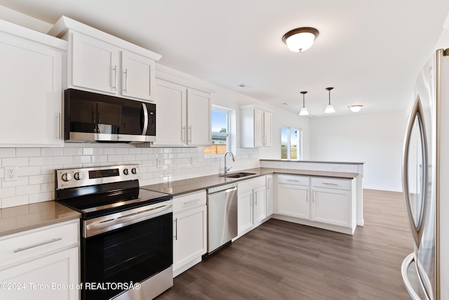 kitchen with pendant lighting, kitchen peninsula, appliances with stainless steel finishes, and white cabinets