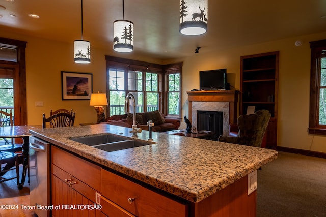 kitchen featuring decorative light fixtures, light stone counters, a premium fireplace, and sink