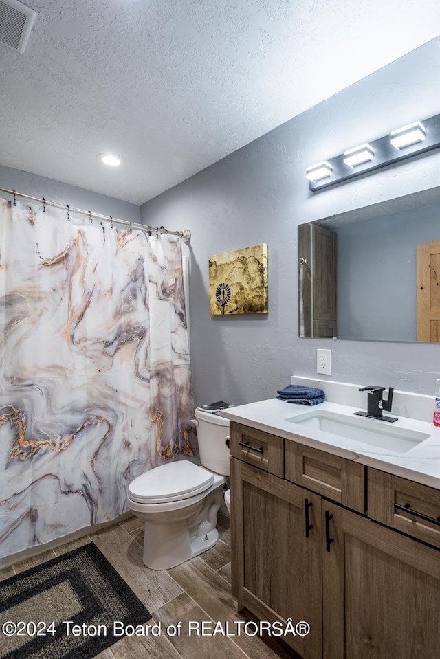 bathroom with vanity, a textured ceiling, and toilet