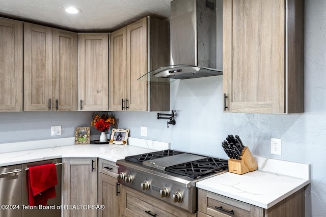 kitchen featuring light stone counters, wall chimney range hood, and stainless steel gas cooktop