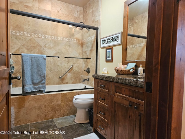 full bathroom featuring vanity, toilet, tile patterned floors, and combined bath / shower with glass door