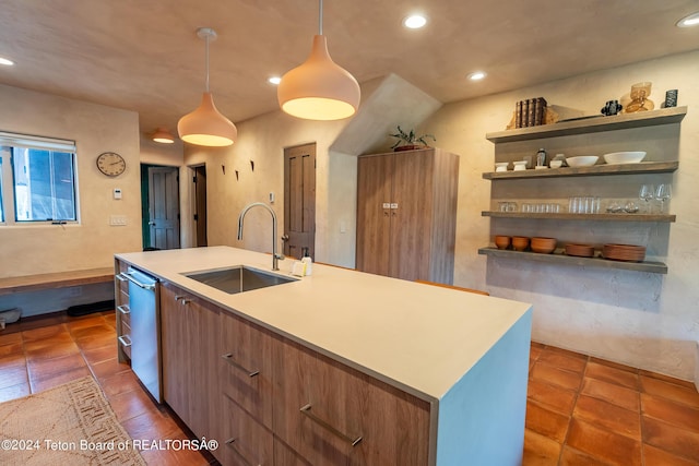 kitchen featuring sink, decorative light fixtures, dishwasher, dark tile patterned floors, and a center island with sink