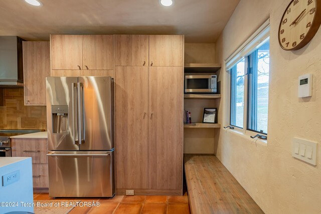 kitchen with stainless steel appliances, wall chimney range hood, and backsplash