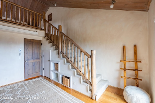 staircase with wood ceiling, high vaulted ceiling, and hardwood / wood-style flooring