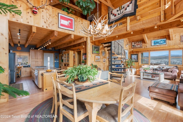 581 E Fork Rd, Dubois, WY 82513 - dining room featuring wooden walls, a chandelier, a high ceiling, a wooden ceiling with exposed beams, and stairway