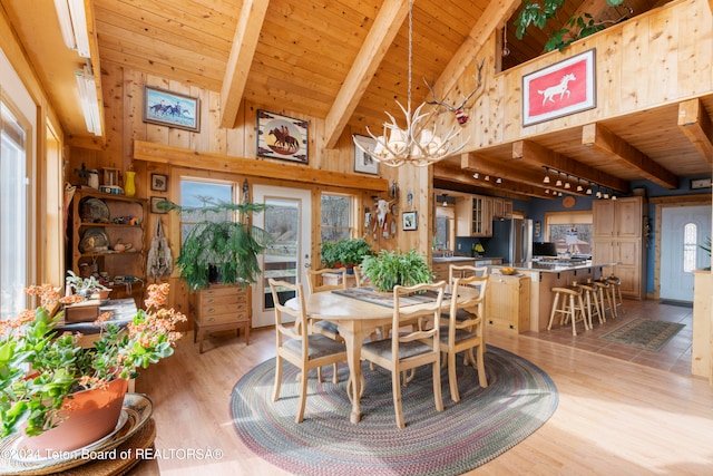 581 E Fork Rd, Dubois, WY 82513 - dining space with a wooden ceiling with exposed beams, light wood-type flooring, wooden walls, a chandelier, and high vaulted ceiling