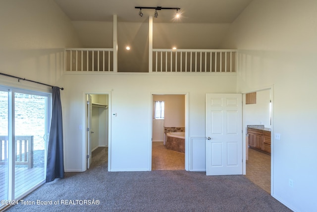 unfurnished bedroom with multiple windows, ensuite bath, high vaulted ceiling, and tile flooring