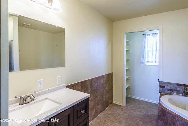 bathroom with vanity, a relaxing tiled bath, and tile flooring