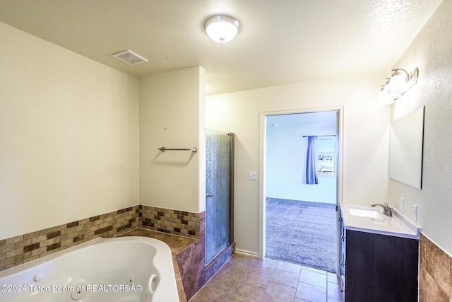 bathroom featuring a textured ceiling, vanity, tile floors, and a washtub