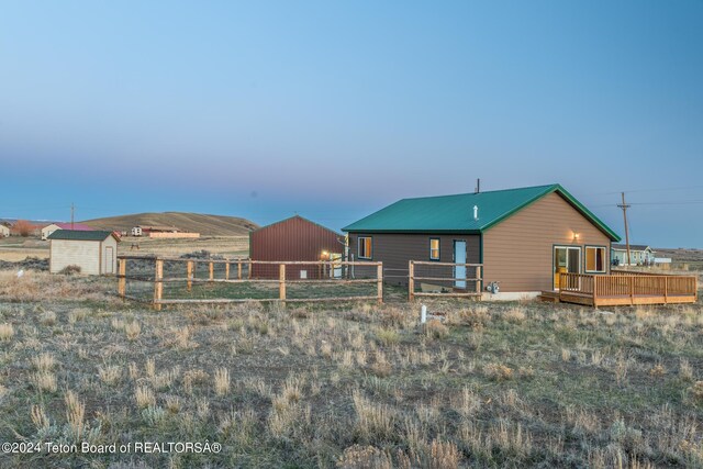 back house at dusk with a deck and a storage unit