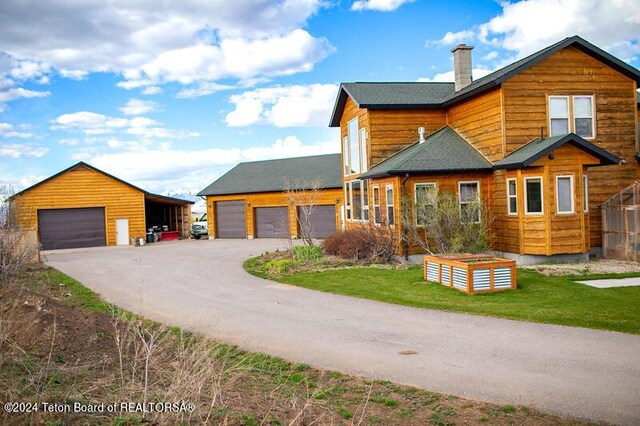 cabin featuring a garage and a front lawn