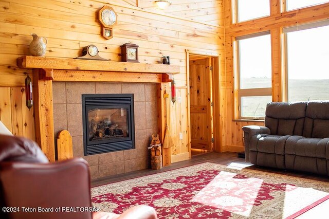 living room with hardwood / wood-style flooring, a fireplace, and wood walls