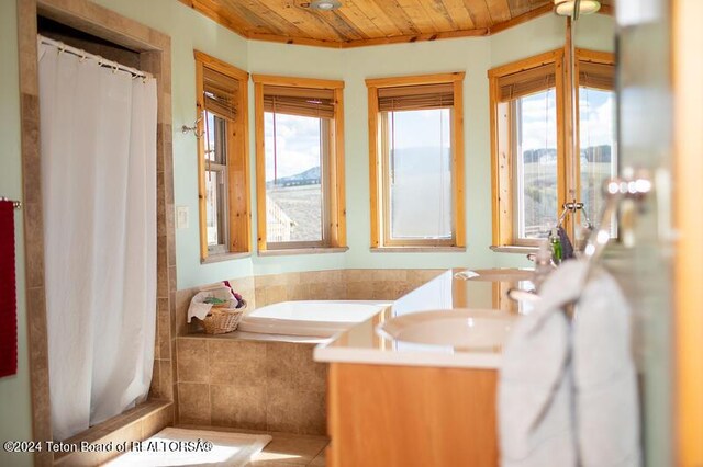 bathroom with tiled tub, vanity, and wooden ceiling