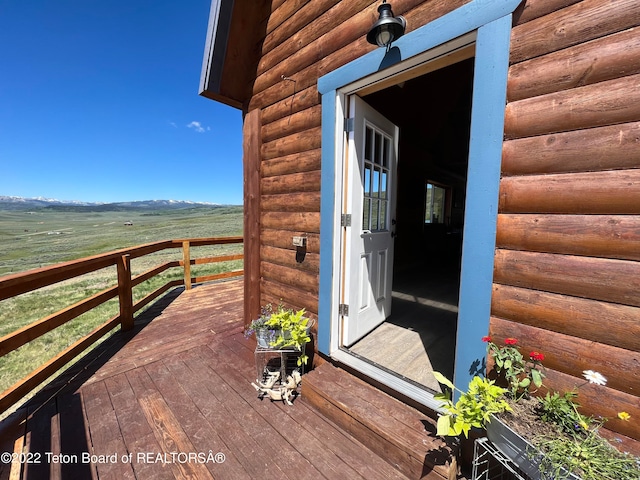 view of exterior entry with a deck with mountain view