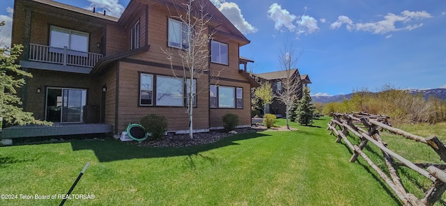 rear view of property featuring a yard and a balcony