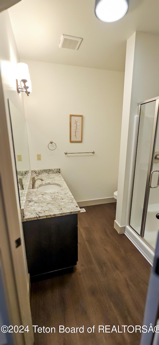 bathroom with a shower with door, vanity, hardwood / wood-style flooring, and toilet