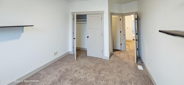 unfurnished bedroom with light carpet and a closet