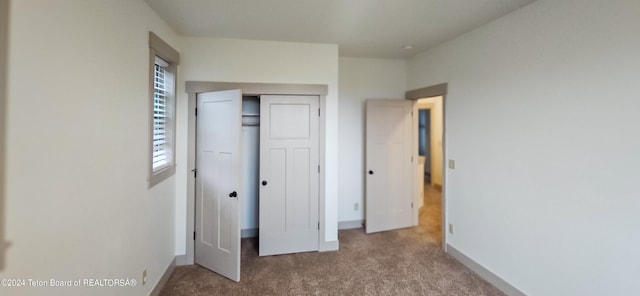 unfurnished bedroom featuring light colored carpet and a closet