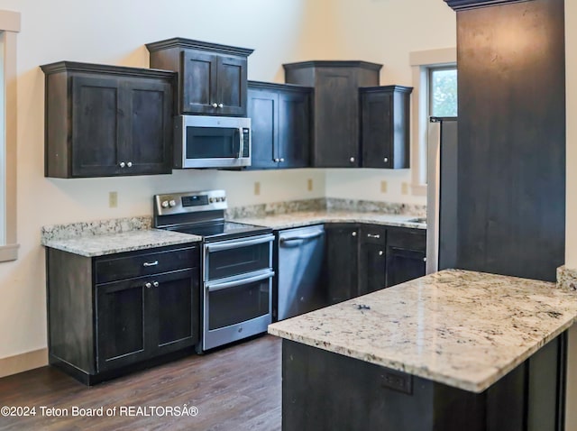 kitchen featuring stainless steel appliances, light stone countertops, and dark wood-type flooring