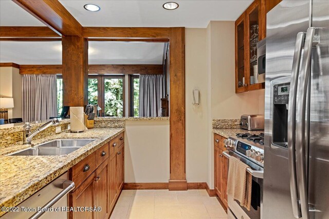 kitchen featuring sink, light stone counters, light tile floors, and appliances with stainless steel finishes