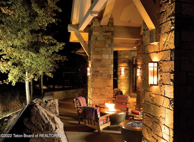 patio terrace at night featuring an outdoor fire pit