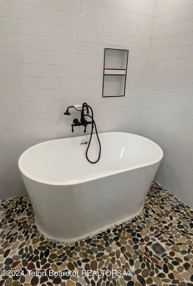 bathroom featuring a tub to relax in, tile walls, and tile patterned floors