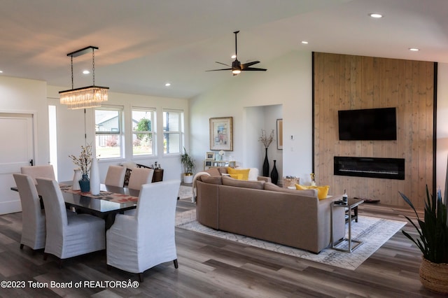 living room featuring a large fireplace, dark hardwood / wood-style floors, vaulted ceiling, and ceiling fan