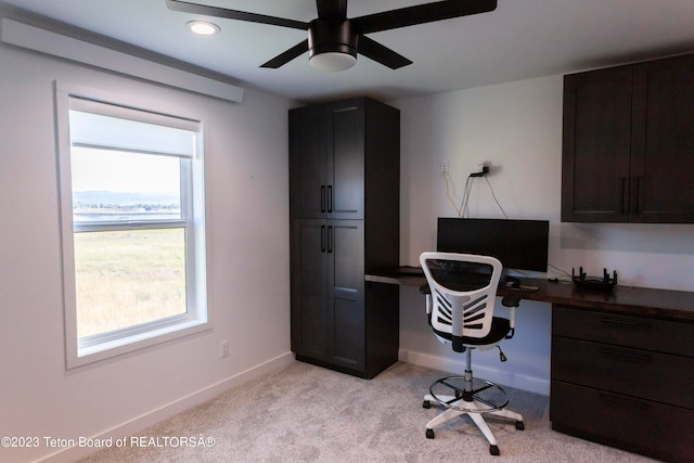 carpeted office with built in desk and ceiling fan