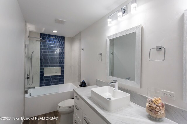 full bathroom with hardwood / wood-style flooring, vanity, toilet, and tiled shower / bath