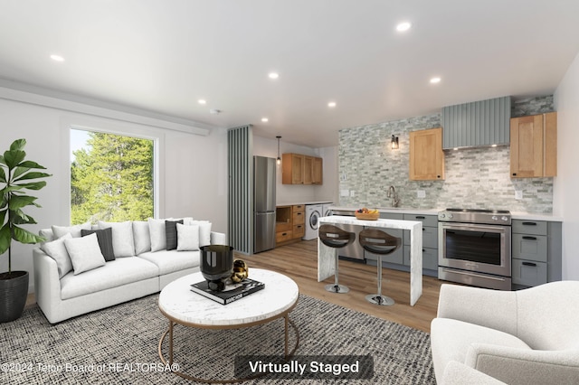 living room with sink, light hardwood / wood-style floors, and washer / dryer