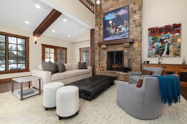 living room featuring a fireplace, beamed ceiling, wood-type flooring, and sink