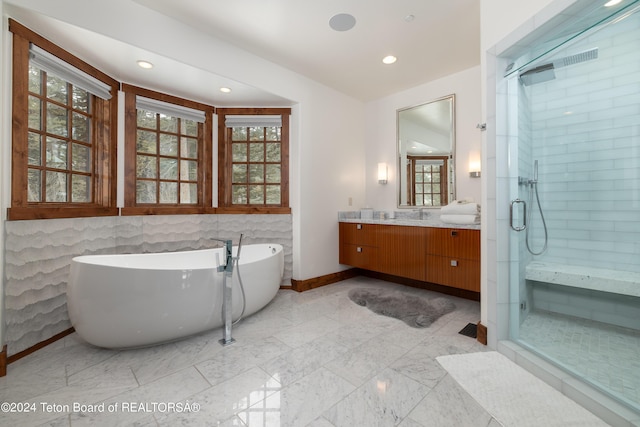 bathroom featuring vanity, a healthy amount of sunlight, and plus walk in shower