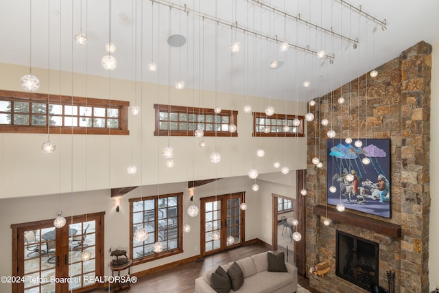 living room featuring a fireplace, french doors, hardwood / wood-style flooring, and high vaulted ceiling