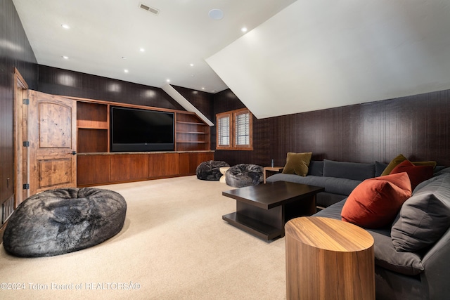 home theater room featuring wood walls, light carpet, and vaulted ceiling