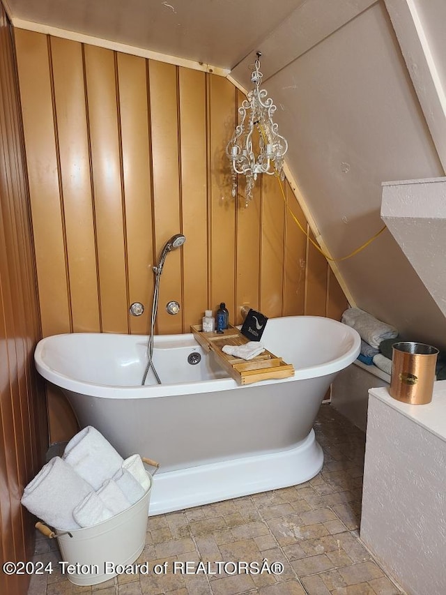 bathroom with tile floors, lofted ceiling, a chandelier, and a washtub