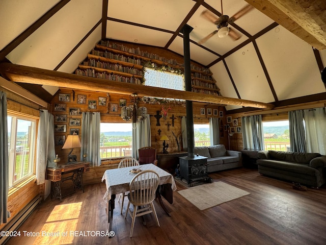 dining room with hardwood / wood-style floors, a wood stove, a baseboard heating unit, high vaulted ceiling, and wood walls