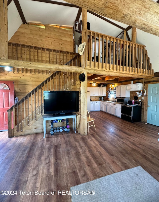 unfurnished living room featuring high vaulted ceiling, wooden walls, and hardwood / wood-style flooring